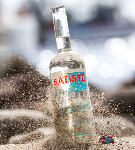 Bottle of Batiste Rhum in sand: California's Batiste Rhum becomes the first carbon negative American craft rum