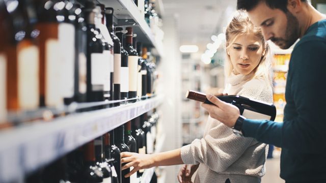 スーパーマーケットで最高のワインを見つける方法:カップルがワインのボトルを選ぶ