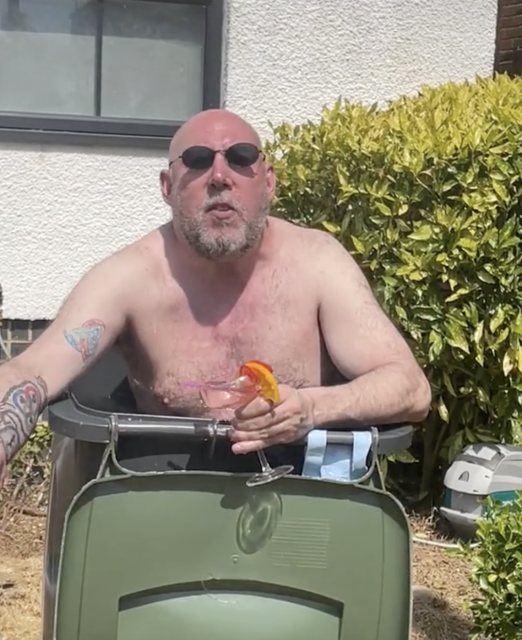 man drinking cocktail in bin full of water