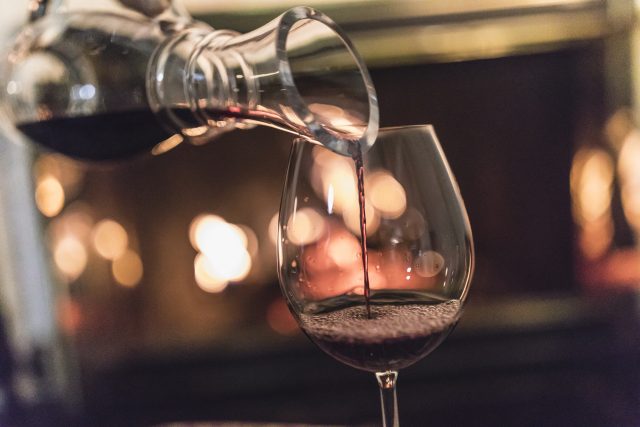 by the glass wine - a decanter pours red wine