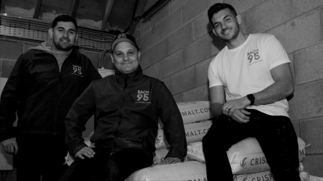 Image of the three Bach 95 founders on grain bags: Rugby pros launch 0% lager ahead of Dry January