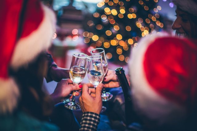 Celebrating Christmas holidays with a group of friends, toasting with champagne: UK drinks sales equal to last Covid-free Christmas