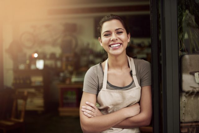 Portrait of a confident young woman standing in the doorway of a coffee shop: The Drinks Trust launches wellbeing day for hospitality workers