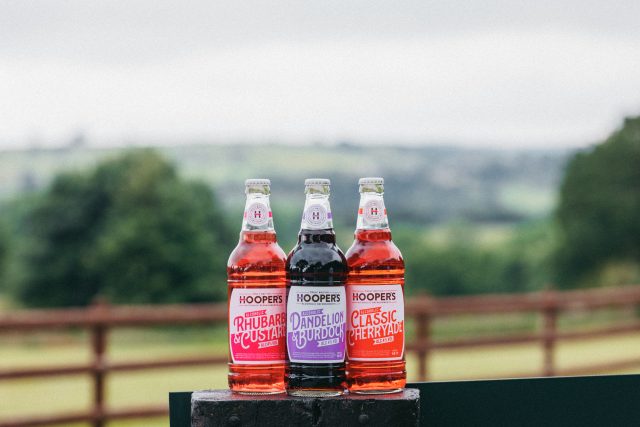 Three bottles of Hooper's overlooking countryside: Global Brands Limited acquires Hooch, Hooper’s and Reef brands from Molson Coors
