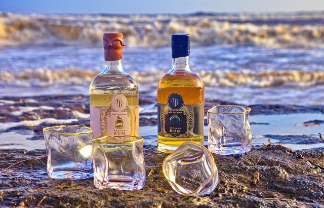 Image of two rum bottles with glasses on the beach: British rum brand seeks £100,000 to launch new bottling