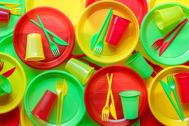 Bright plastic disposable tableware background: Hospitality industry responds to ban on single-use plastics