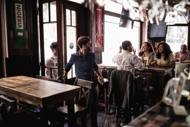 Amigos reunidos en un pub después del trabajo, viendo un partido de fútbol: Los aficionados a los bolos acuden a los pubs en este "enero seco