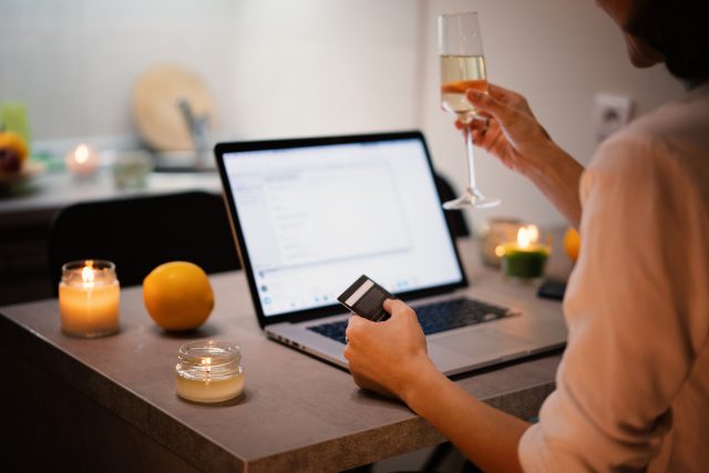 Online internet shopping with a glass of champagne in hand, merry christmas and new year concept: Majestic trumps Waitrose Cellar as top online alcohol retailer, research finds