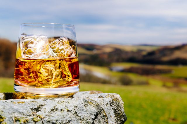 Glass of whisky on the rocks, literally and metaphorically, outdoors in the Scottish Highlands.: Scotch whisky exports hit record £6 billion in 2022