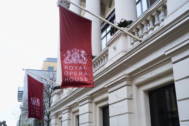 Large red banners in front of the Royal Opera House, depicting the Royal coat of arms, ahead of Christie's wine auction.