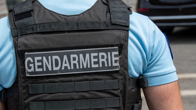 Close-up "GENDARMERIE" marking written on the back of a bulletproof vest worn by a French gendarme.
