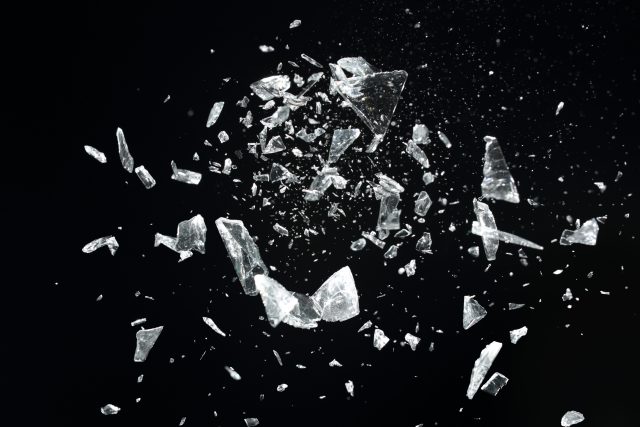 Exploding glass pieces, studio shot, selective focus.