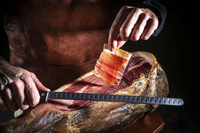 Iberian ham serrano ham cutting slice male hands and knife 